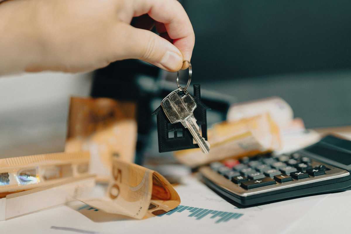 A person holding keys with $50 bills spread on the table along with a calculator - Representative Image Source: Pexels | Jakub Zerdzicki