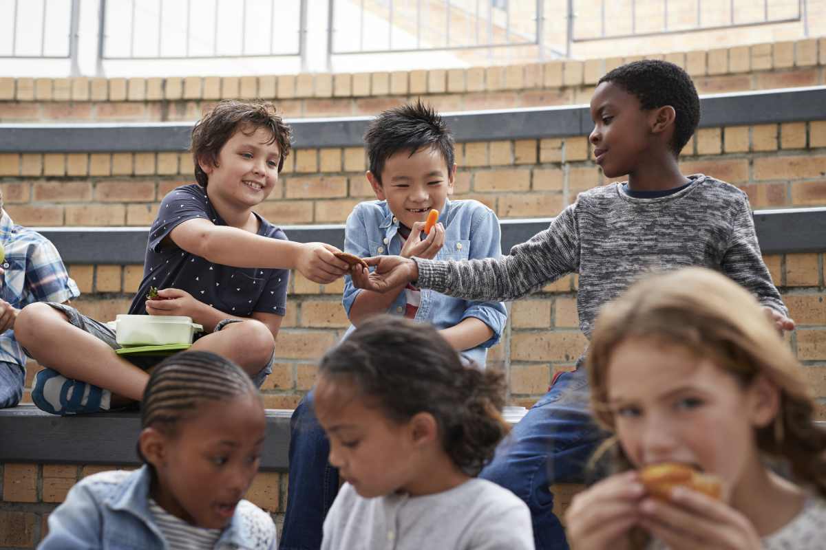 School children having lunch together outside the building - Representative Image Source: Getty Images | Photo by Klaus Vedfelt