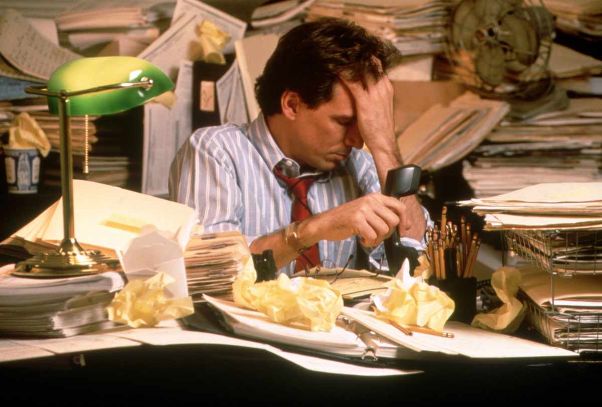 A stressed man is surrounded by exhausting paperwork in the office. (Representative Image Source: Getty Images | Photo by David Pollack)