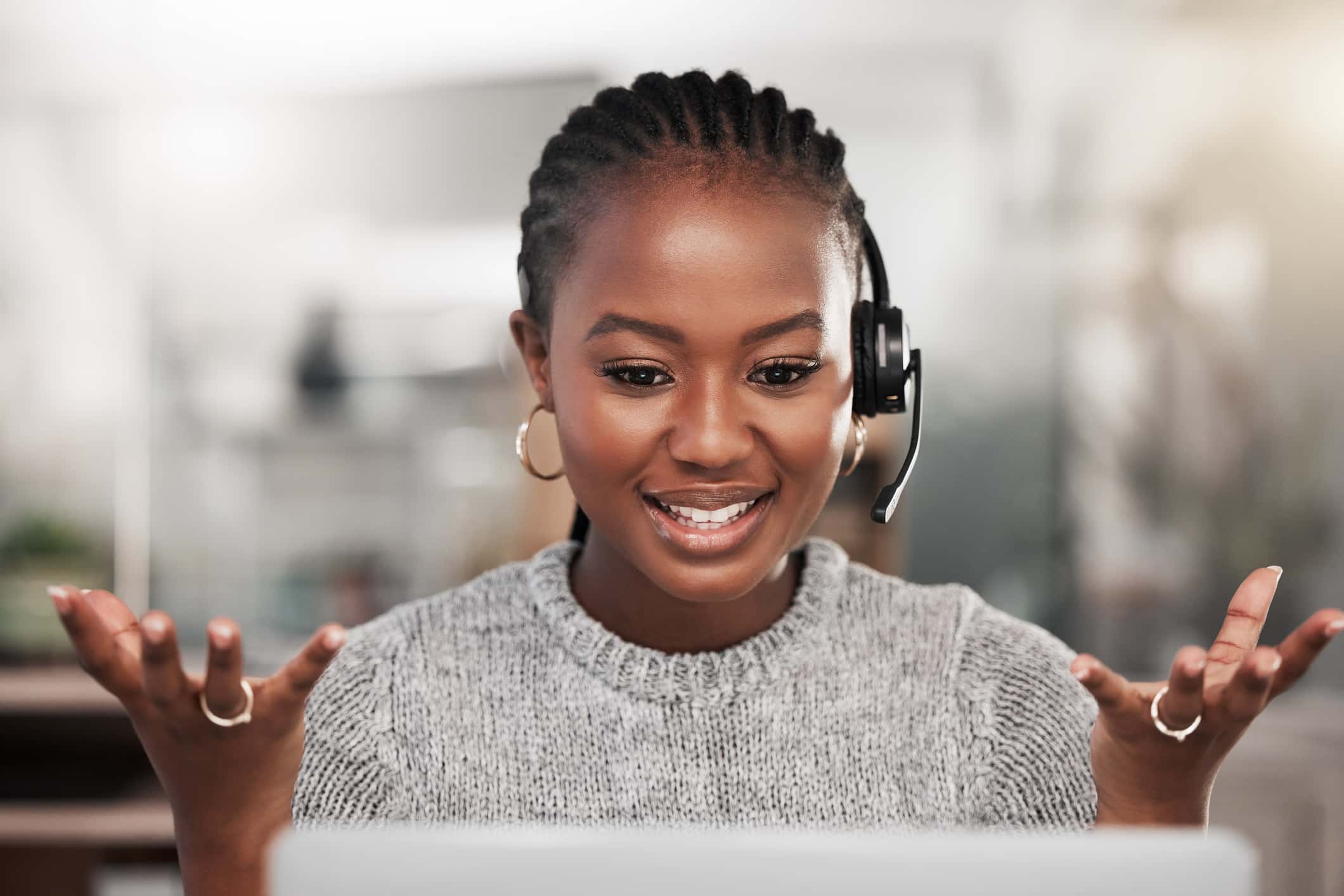 Shot of a young woman using a headset and laptop in a modern office - stock photo/Getty Images