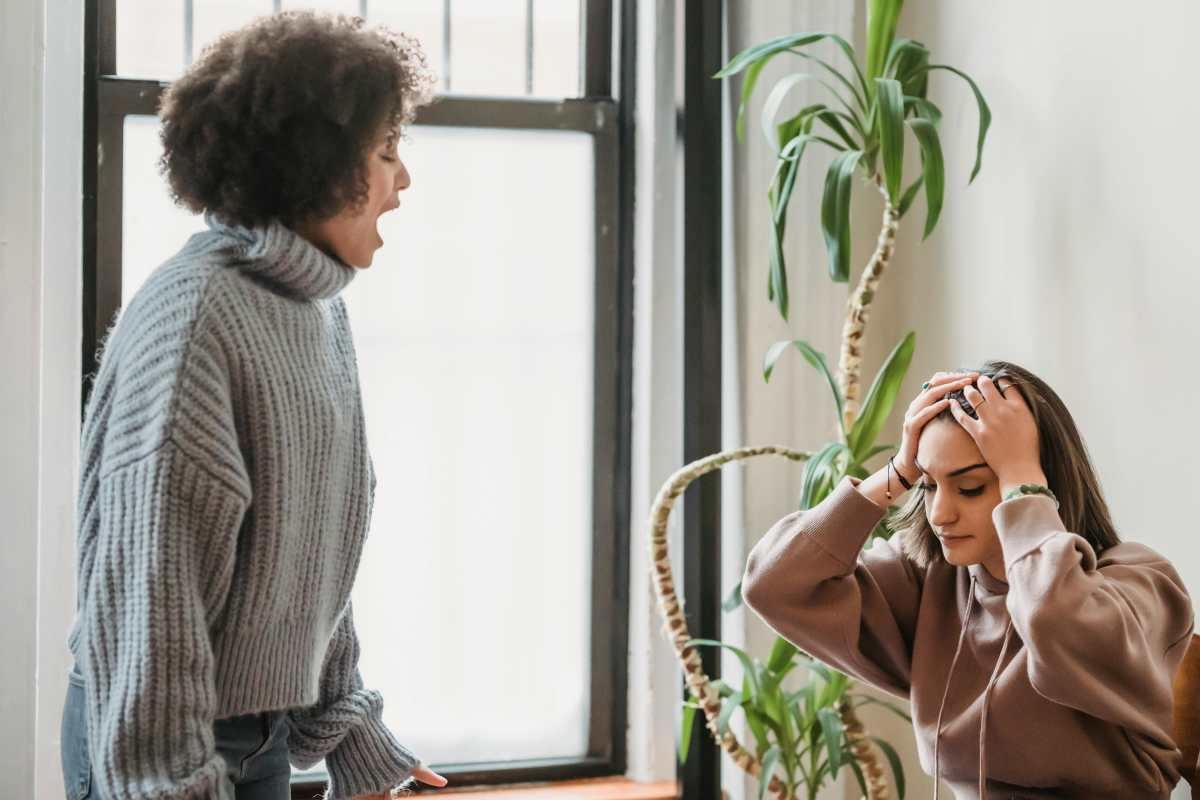 Woman holds her head in agitation as another woman makes upsetting remarks (Representative Image Source: Pexels | Liza Summer)